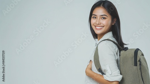 Smiling young Filipino female student in profile view, with olive green backpack and light shirt, isolated on light gray background.