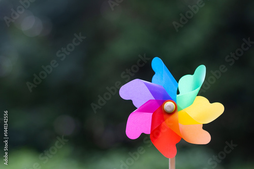 caucasian baby girl playing with pinwheel toy in the park at summer day. happy family lifestyle kid dream concept. daughter plays with a toy windmill outdoor