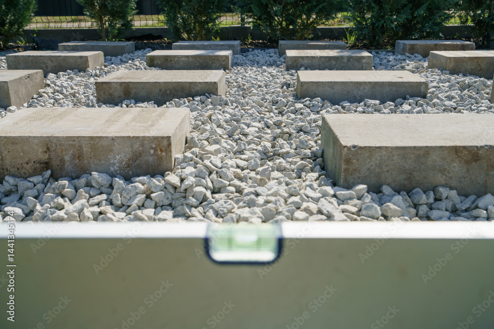 Spirit level on top of concrete blocks. Preparation for garden shed foundation