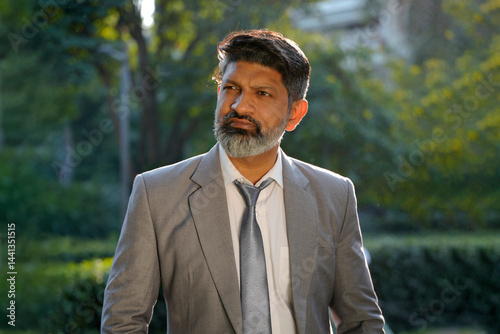 Deep thinking indian corporate man in public park