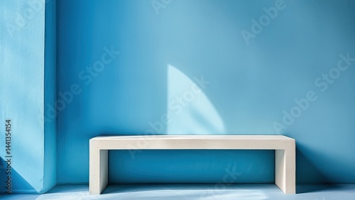 A minimalist modern interior featuring a simple white bench against a bright blue wall with geometric shadows, creating a serene and elegant atmosphere.