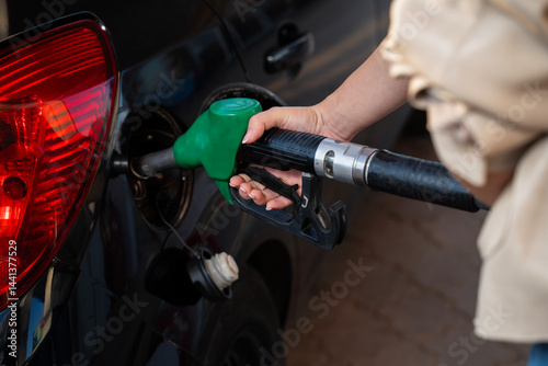 Closeup shot of woman hand filling up the gas tank of a black car 