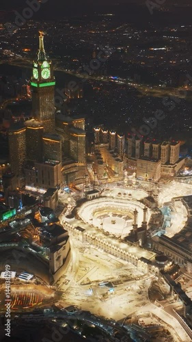 Stunning aerial view of the illuminated Grand Mosque and towering Abraj Al Bait Clock Tower in Mecca, Saudi Arabia at night with glowing city lights