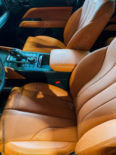 The interior of the car showcases stunning brown leather seats and a sleek, modern console, which collectively enhance its overall luxurious appeal and make it truly stand out on the road