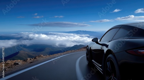 Black sports car driving on a winding mountain road high above the clouds under a clear blue sky.
