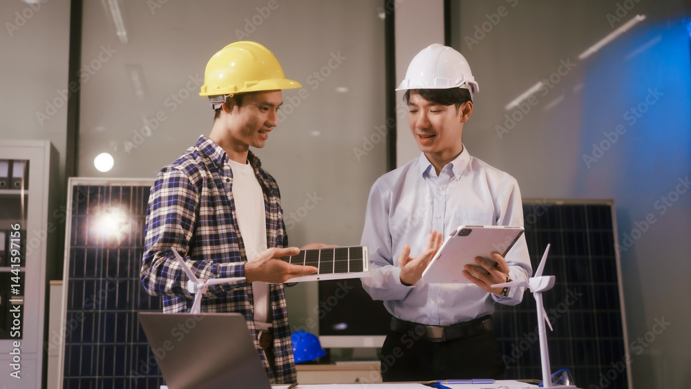 Two Asian businessmen wearing engineer hats table, discussing solar panels and wind turbines. They plan environmental projects, focusing on solar energy solutions and renewable energy installations Two Asian businessmen wearing engineer hats table, discussing solar panels and wind turbines. They plan environmental projects, focusing on solar energy solutions and renewable energy installations