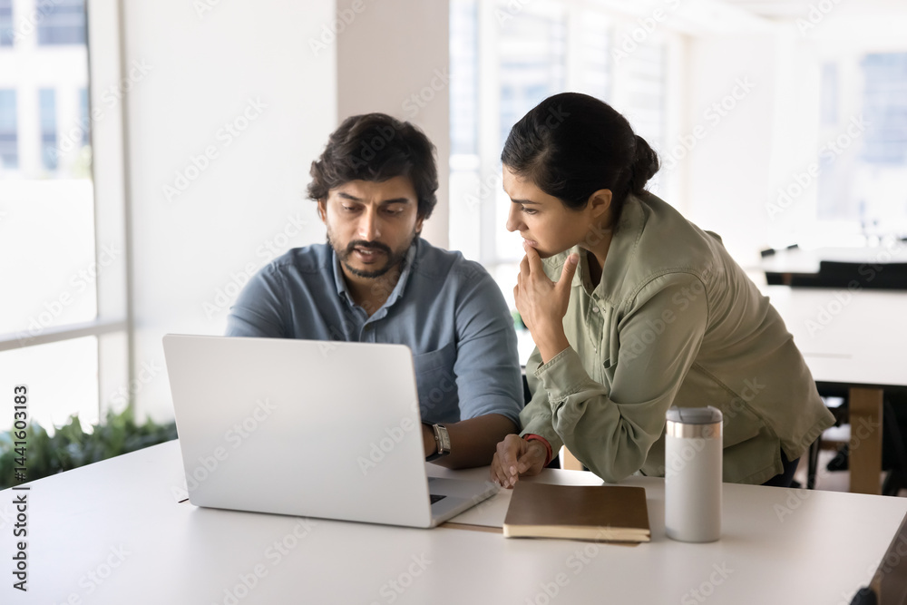 Two Indian teammates analyze data, working on joint project using modern laptop, look at spreadsheets, reports, or analytics, making decisions, solve work-related matters, generate business strategy Two Indian teammates analyze data, working on joint project using modern laptop, look at spreadsheets, reports, or analytics, making decisions, solve work-related matters, generate business strategy