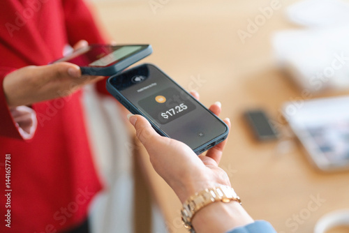 A customer is paying $17.25 with their phone. The cashier is holding their phone to accept the payment. Contactless payments are a fast and easy way to pay.