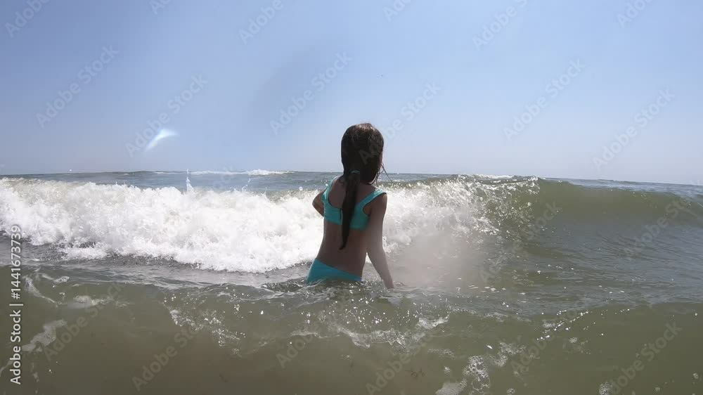 Slow motion view of sea waves splashing on kid girl during summer vacation Slow motion view of sea waves splashing on kid girl during summer vacation