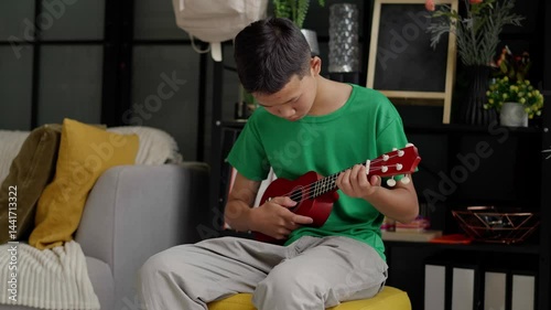 Asian boy learning to play ukulele