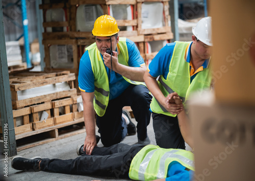 Emergency response in warehouse setting with safety workers assisting injured person on industrial floor