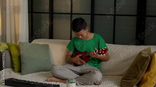 Asian boy learning to play ukulele