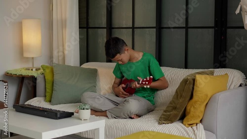 Asian boy learning to play ukulele
