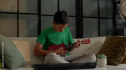 Asian boy learning to play ukulele