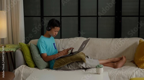 Asian boy studies online on laptop at home