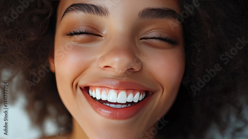 Obraz na płótnie A young woman with curly hair smiles broadly, showcasing her bright teeth, radiating happiness in a cozy indoor setting w salonie