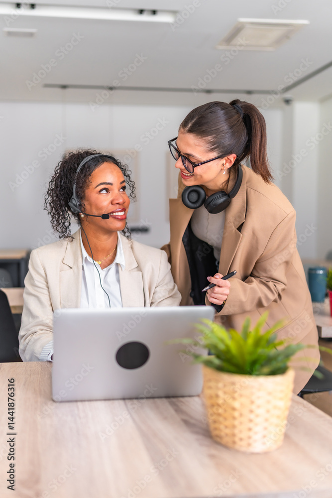 Two businesswomen collaborating on a laptop in office environment