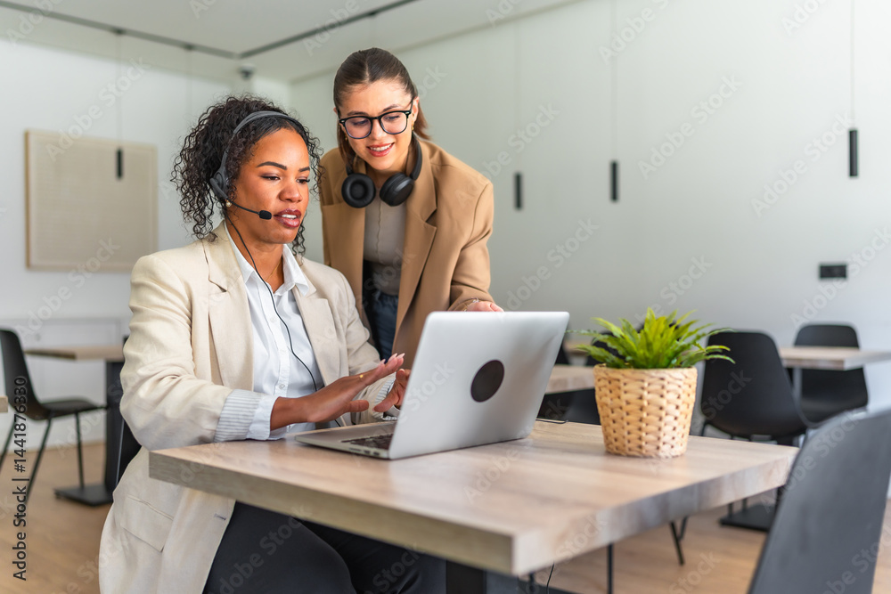 Telemarketers working together on a laptop in modern office