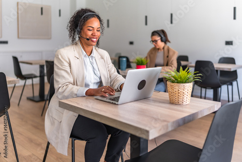 Smiling black customer service representative working on laptop in coworking space