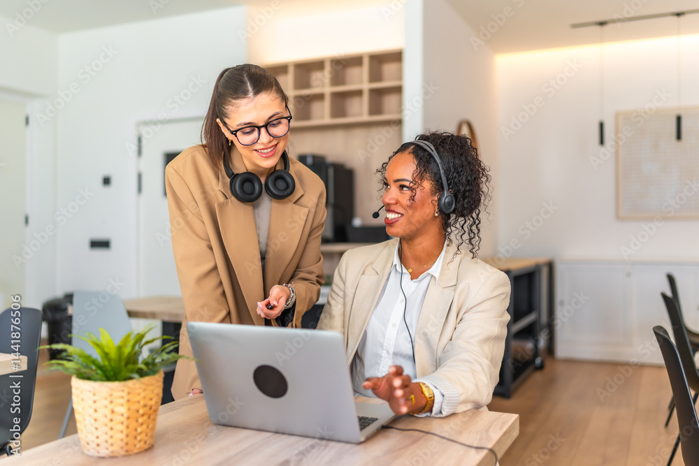 Two businesswomen collaborating on laptop in modern office