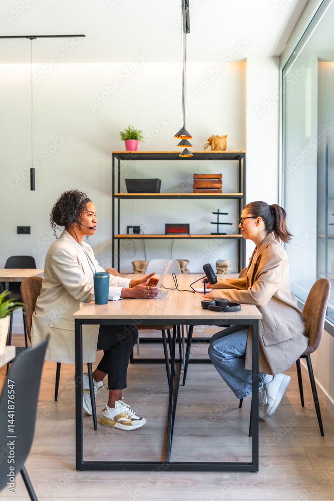 Two businesswomen recording a podcast in modern office