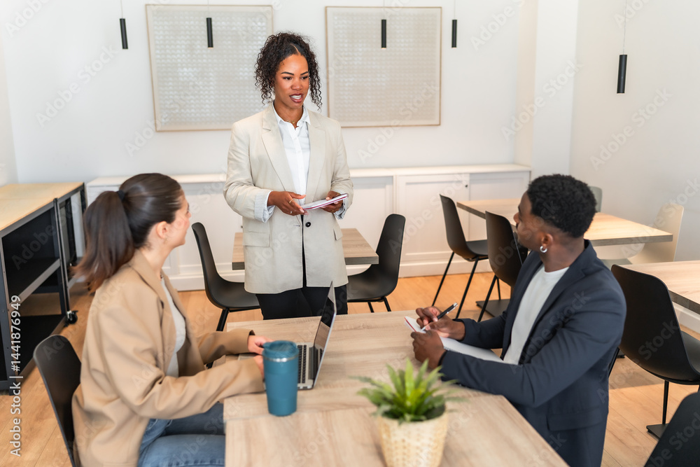 Businesswoman leading meeting with two colleagues taking notes in modern office