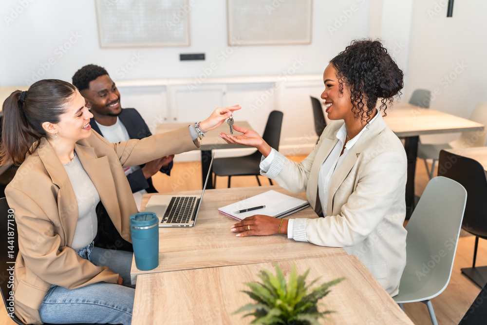 Real estate agent giving keys to happy couple after successful deal