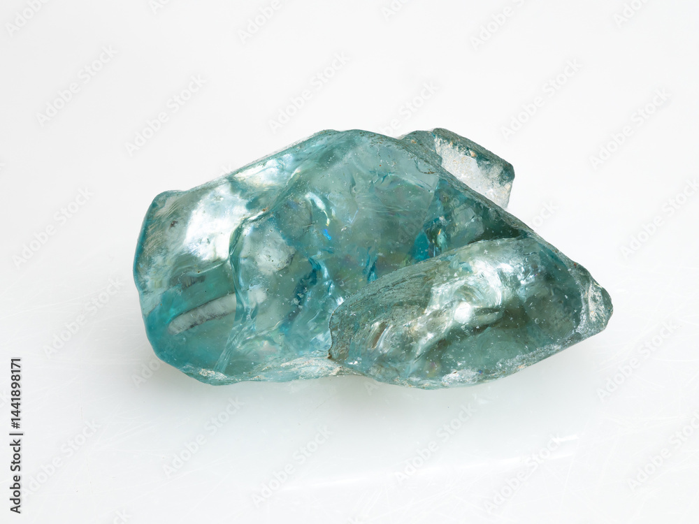 A close-up studio shot of a raw, translucent blue natural zircon crystal against a dark background showcasing its irregular facets and internal reflections