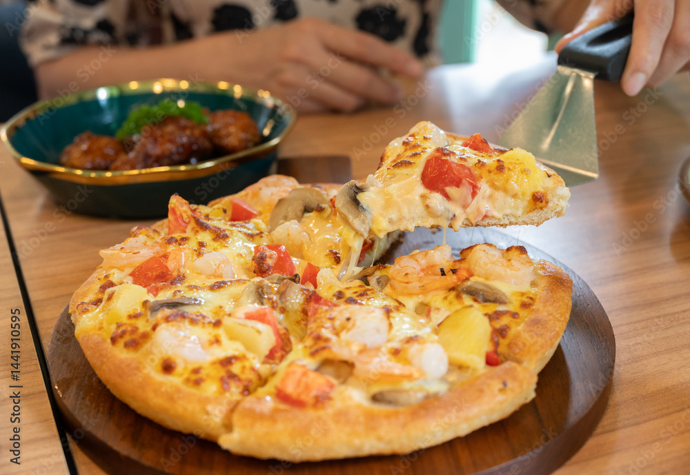 Someone using a pizza peel for separate a piece of pizza before eating. Pizza, a staple of Italian cuisine, has become one of the most recognizable and popular dishes worldwide.