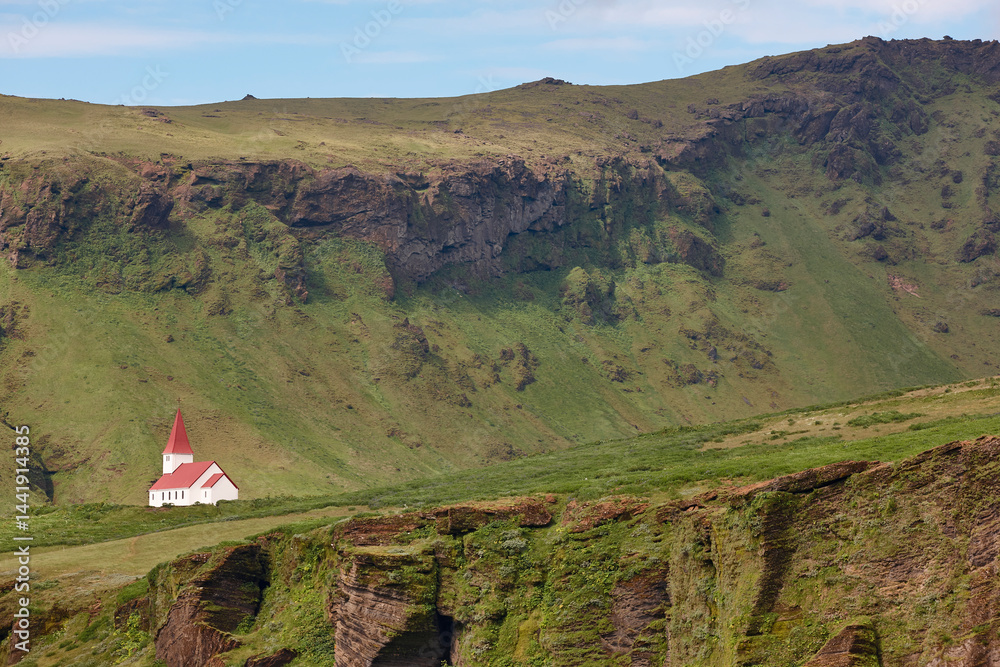 Traditional chapel with red roof in Vik. Mountain landscape. Iceland