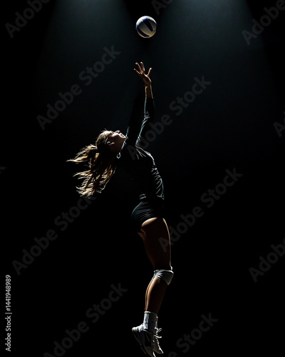 Female volleyball player leaping to spike the ball in dramatic low-key lighting.