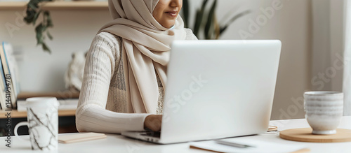 Obraz na płótnie Bright Workstation: White desk with laptop, mug and notepad, hijabi woman typing in soft-focus w salonie