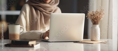 Obraz na płótnie Student or professional hijabi typing on laptop, Scandinavian design setting, perfect for work or study themes w salonie
