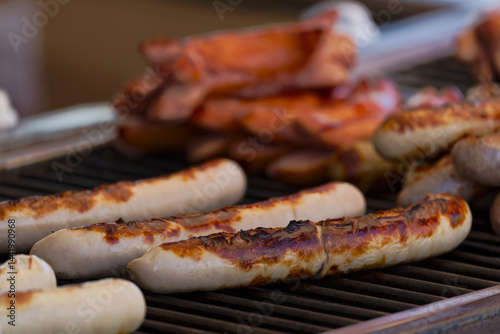 Close-up of frying sausages heated on grill at town square named Bellevue at Swiss City of Zürich on a spring day. Photo taken April 28th, 2025, Zurich, Switzerland.
