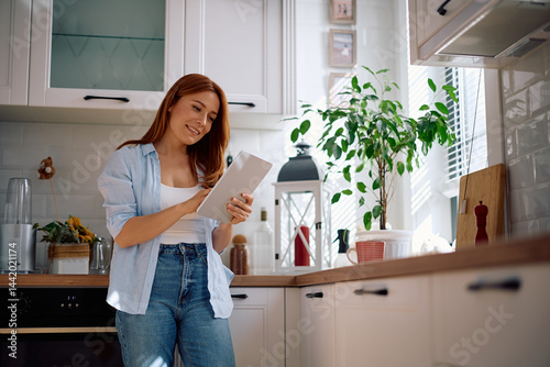 Happy woman using digital tablet in kitchen. photo