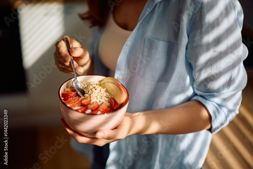 Photos Close up of woman having oatmeal topped with fresh fruit at home.