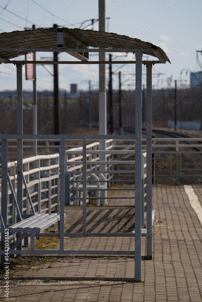 a bus shelter made of metal structures on the platform of a railway station