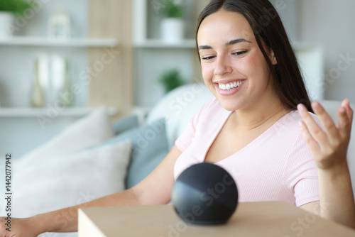Happy woman is talking to smart speaker at home Free Download Happy woman is talking to smart speaker at home - GFXLoad