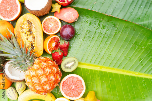 Fototapeta Naklejka Na Ścianę i Meble -  Summer mix of tropical fruits over green leaf with copy space