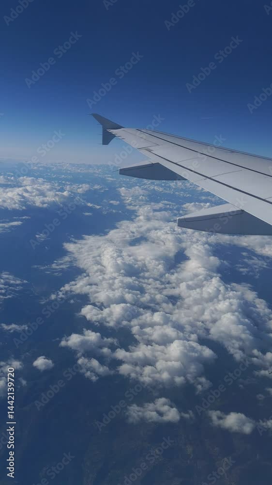View through the window of an airplane wing, clouds, mountains and the ground from above. View through the window of an airplane wing, clouds, mountains and the ground from above.