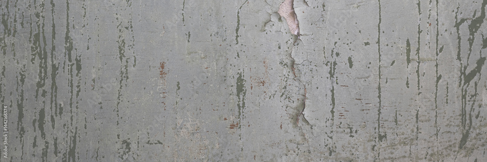 Peeling paint on the wall. Panorama of a concrete wall with old cracked flaking paint. Weathered rough painted surface with patterns of cracks and peeling. Wide panoramic texture for grunge background