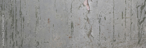 Peeling paint on the wall. Panorama of a concrete wall with old cracked flaking paint. Weathered rough painted surface with patterns of cracks and peeling. Wide panoramic texture for grunge background