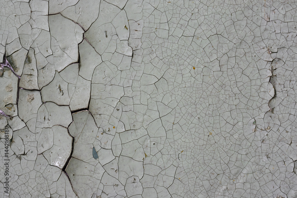 Peeling paint on the wall. Old concrete wall with cracked flaking paint. Weathered rough painted surface with patterns of cracks and peeling. High resolution texture for background and design. Closeup