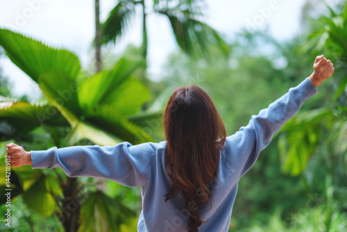 Rear view image of a woman opening arms and do stretching in the garden
