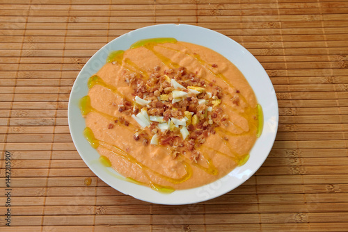 Obraz na płótnie A white plate with a delicious red soup topped with bacon bits. The bacon is spread out across the surface of the soup, creating a visually appealing presentation w salonie