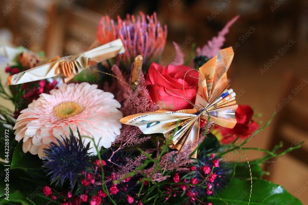Flowers with origami - a bouquet with red and pink blooms, decorated with european money folded as butterflies