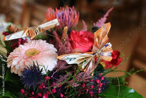 Obraz na płótnie Flowers with origami - a bouquet with red and pink blooms, decorated with european money folded as butterflies w salonie