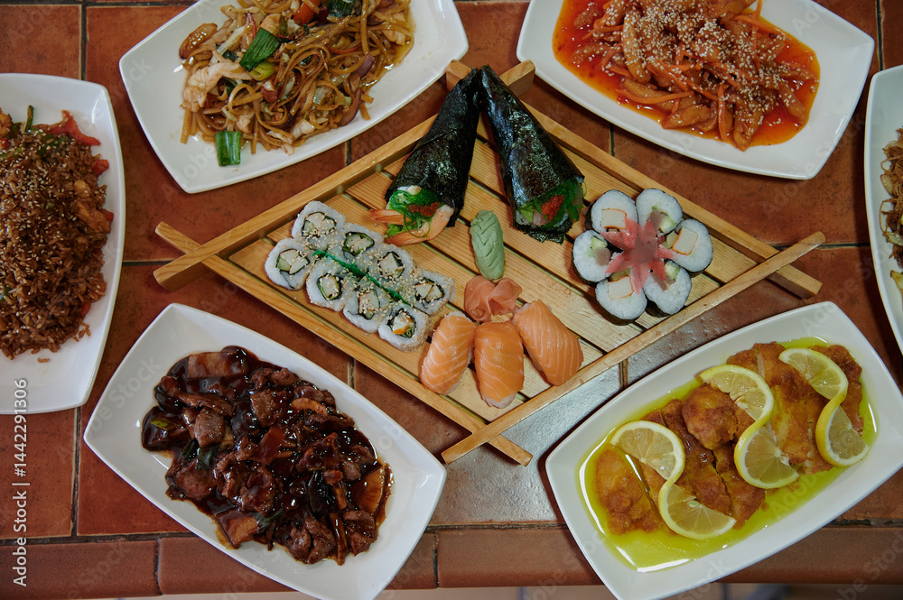 A table with many different types of food, including sushi, chicken, and lemon. There are also some bowls and plates on the table