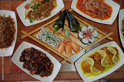 Obraz na płótnie A table with many different types of food, including sushi, chicken, and lemon. There are also some bowls and plates on the table w salonie