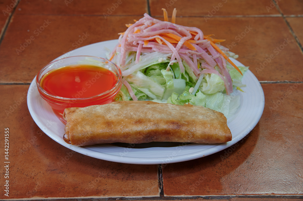 A plate of food with a piece of fried food and a salad. The salad has carrots and ham